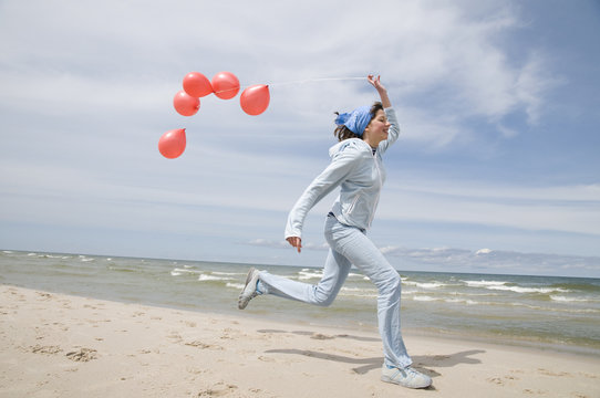 Teenager playing with balloons on the beach