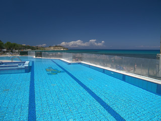 Blue swimming pool by sea.