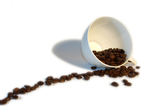 tilted cup with coffee beans