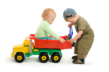 Two little boys play with toy truck