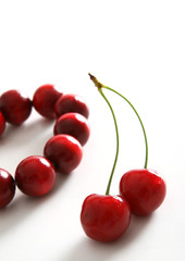 pair of Fresh cherry's next to red beads