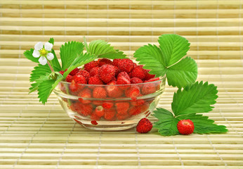 red strawberry fruits with green leafs in glass vase
