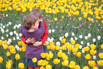 Children embrace each other on  field of tulips