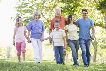 Extended family walking in park holding hands and smiling