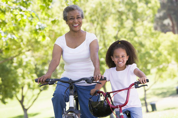 Fototapeta na wymiar Grandmother and granddaughter on bikes outdoors smiling
