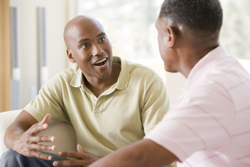 Two men in living room talking and smiling - Powered by Adobe