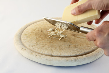 Käse reiben über einem Holzbrett