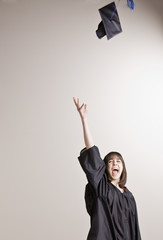 Female graduate throwing cap into the air