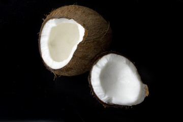 a coconut cracked in two on a black background