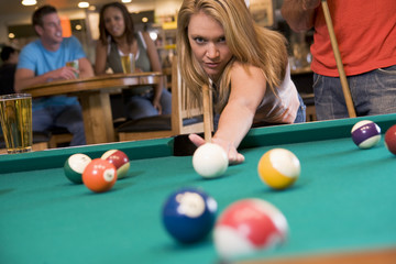Young woman playing pool in a bar