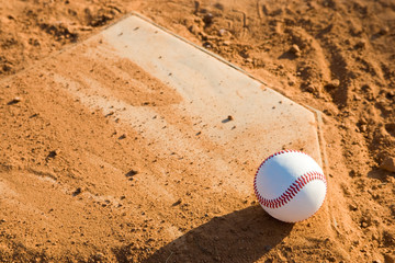 Baseball Sitting on a dirty homeplate.