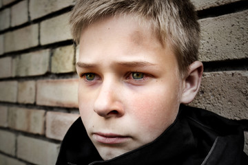 upset boy leaning against a wall