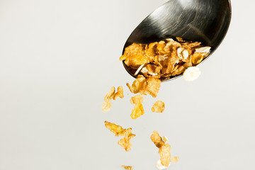 Cereals poured from a table spoon on grey background