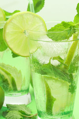 Two mojito cocktails on green background