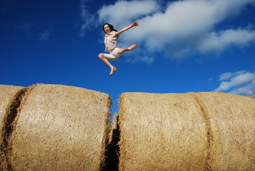 fillette sautant sur des meules de foin