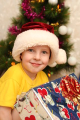The boy in a New Year's cap and a gift