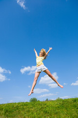 Happy young woman is jumping in a field