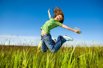 Happy young woman is jumping in a field