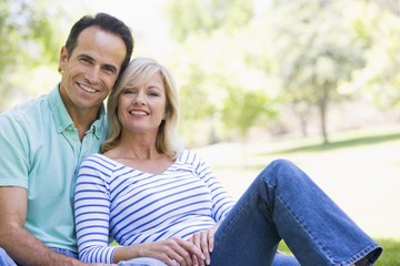 Fototapeta na wymiar Couple relaxing outdoors in park smiling