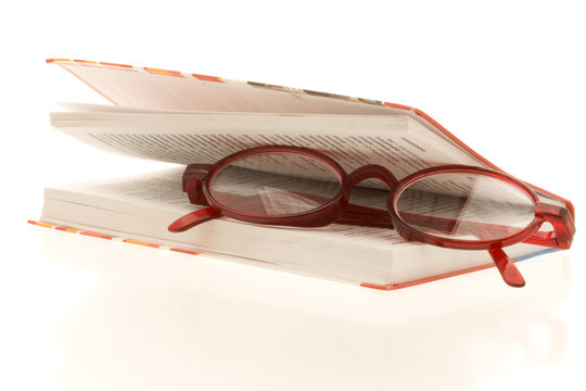 Red Reading Glasses Between A Almost Closed Book