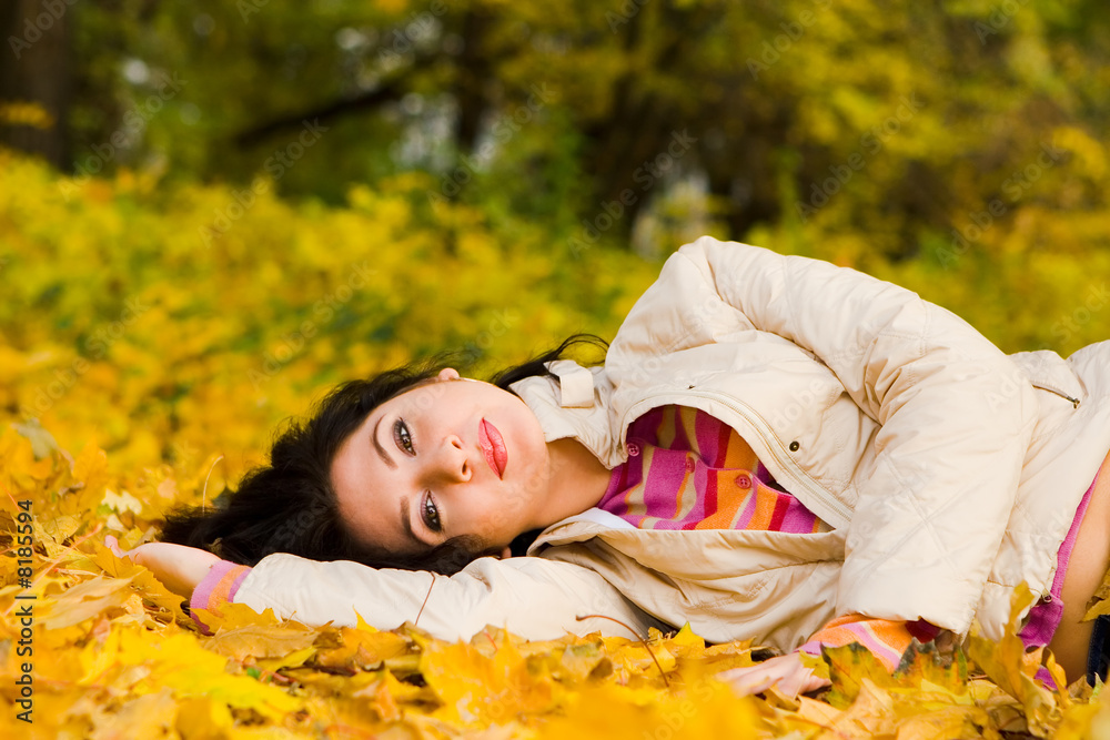 Wall mural young pretty woman on the autumn leaf