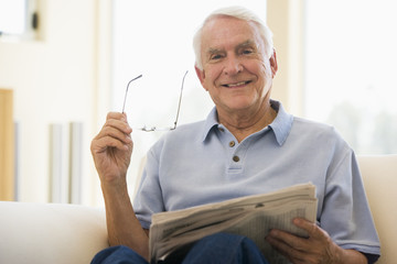 Man in living room reading newspaper