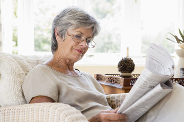 Woman in living room reading newspaper