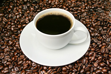 Freshly brewed coffee over dark roasted coffee beans