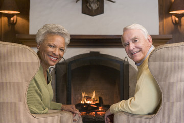 Couple sitting in living room by fireplace smiling