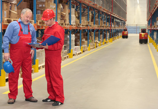 standing workers in warehouse reading invoice