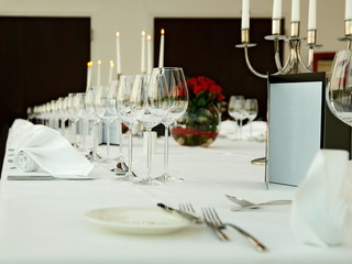 eleganter Banketttisch mit einer Reihe von Weingläsern, roten Rosen und Kerzenlichtern