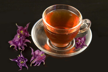 Transparent teacup with tea and flowers