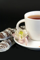 White teacup with tea, cookies and flowers