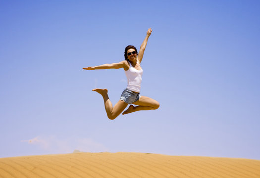 Young girl jump on the sand  
