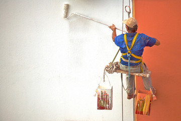 Hanging Painter painting wall with roller - obrazy, fototapety, plakaty