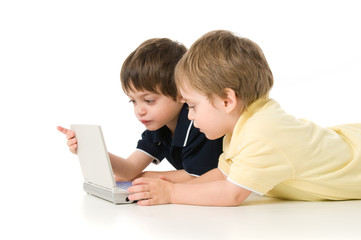 Two children playing with the laptop lying on the floor