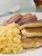 Pancakes with Crispy Bacon, Scrambled Eggs and Maple Syrup