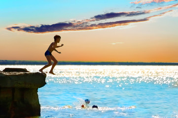 The boy jumping in water from a pier