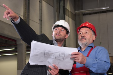 businessmen and older worker over blueprints