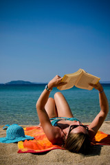 woman in bikini reading on the beach