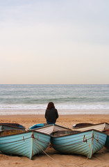 Fototapeta premium lonely person with boats, beach and sea in sunset light