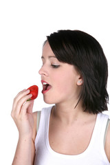 Healthy young woman eating a strawberry