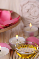 spa products with rose petals, oil container, towel and candles