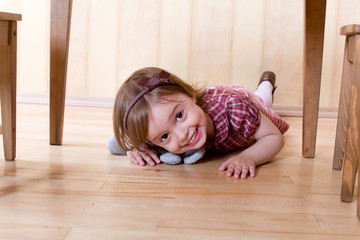 Happy little girl crawling on the hardwood floor