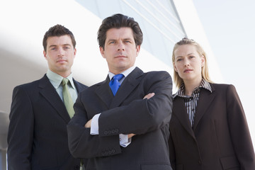 Three businesspeople standing outdoors by building