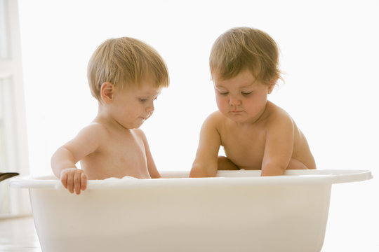 Two babies playing in bubble bath