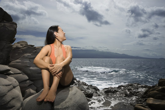 Woman sitting by ocean