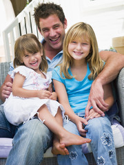 Man and two young girls sitting on patio smiling