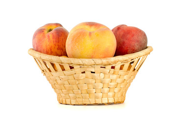 Three tasty peaches in wicker basket