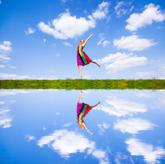 Fototapeta na wymiar Happy girl jumping together on green meadow. Reflected in water